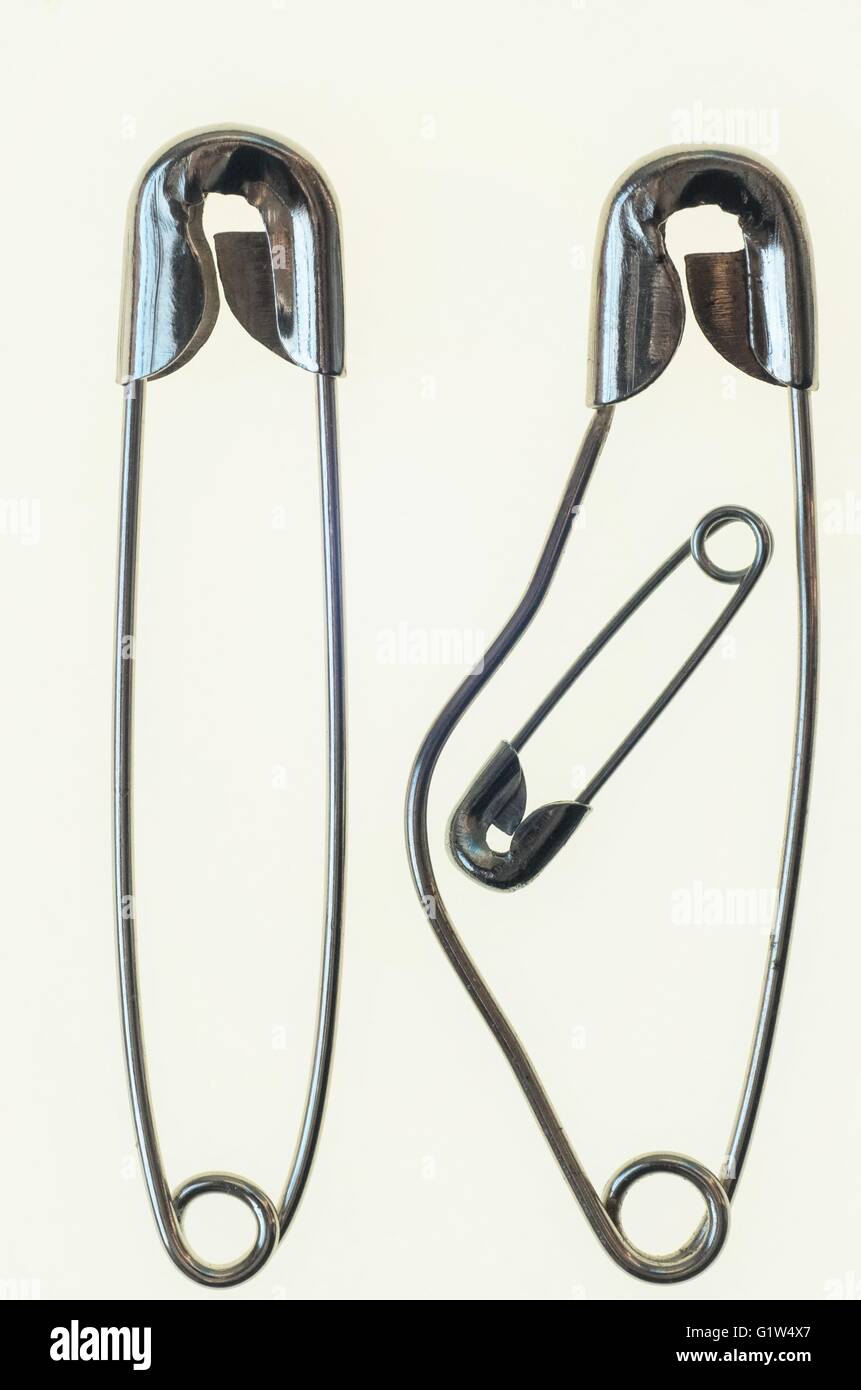 three safety pins for a minimalistic composition representing a couple with  the woman pregnant, and the fetus is the little one Stock Photo - Alamy