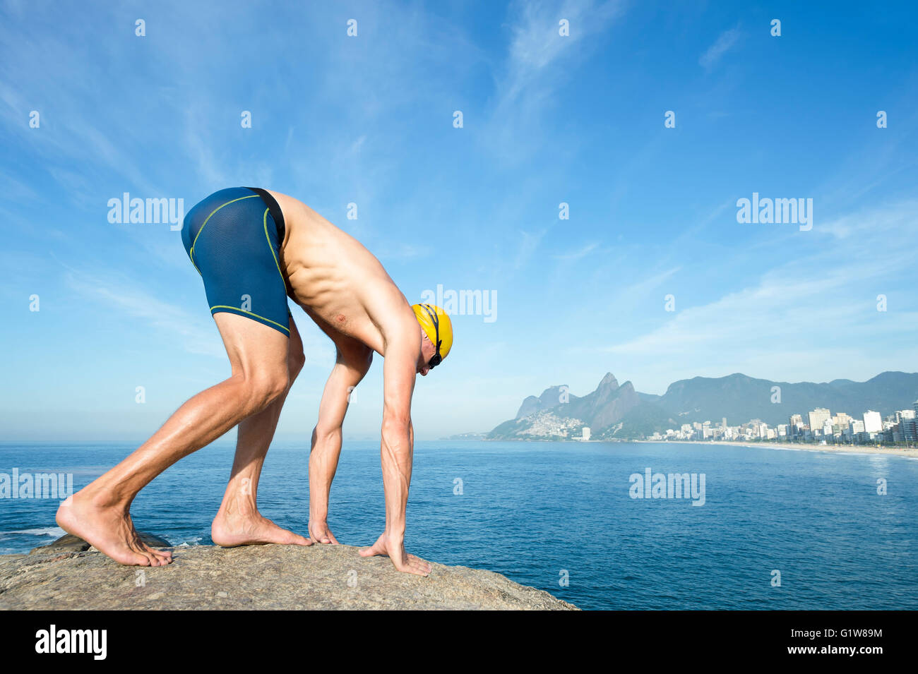 Pool Crounching Athlete swimmer with yellow swimming cap crouching in the start ...