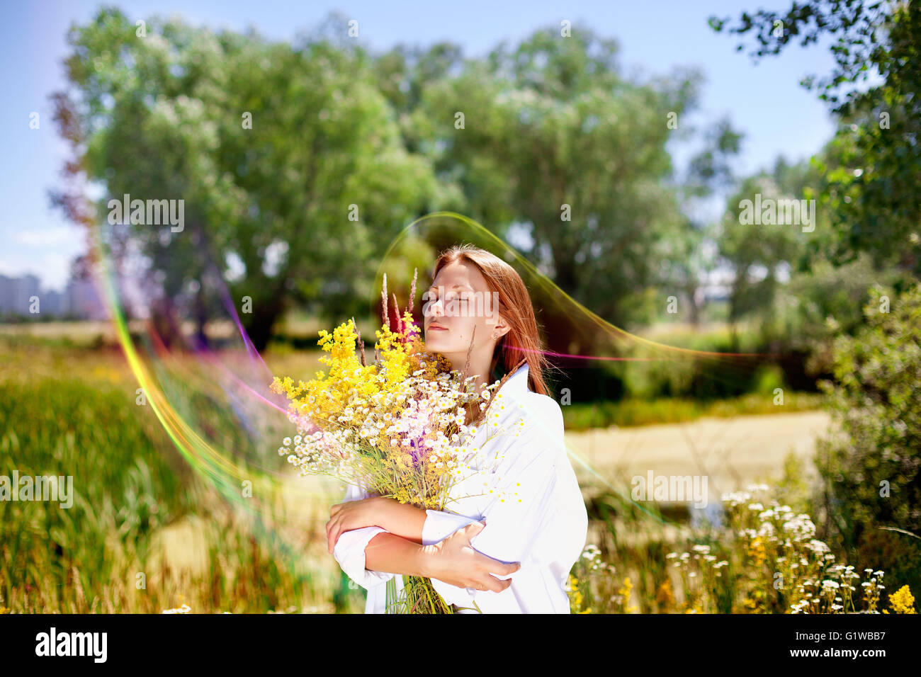 The girl holds a bouquet of wild flowers in hand. Stock Photo