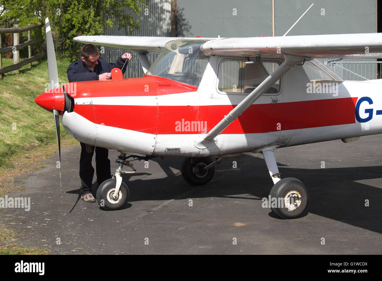 Pilot checks the wing fuel tanks of a flying club Cessna 152 in the UK Stock Photo