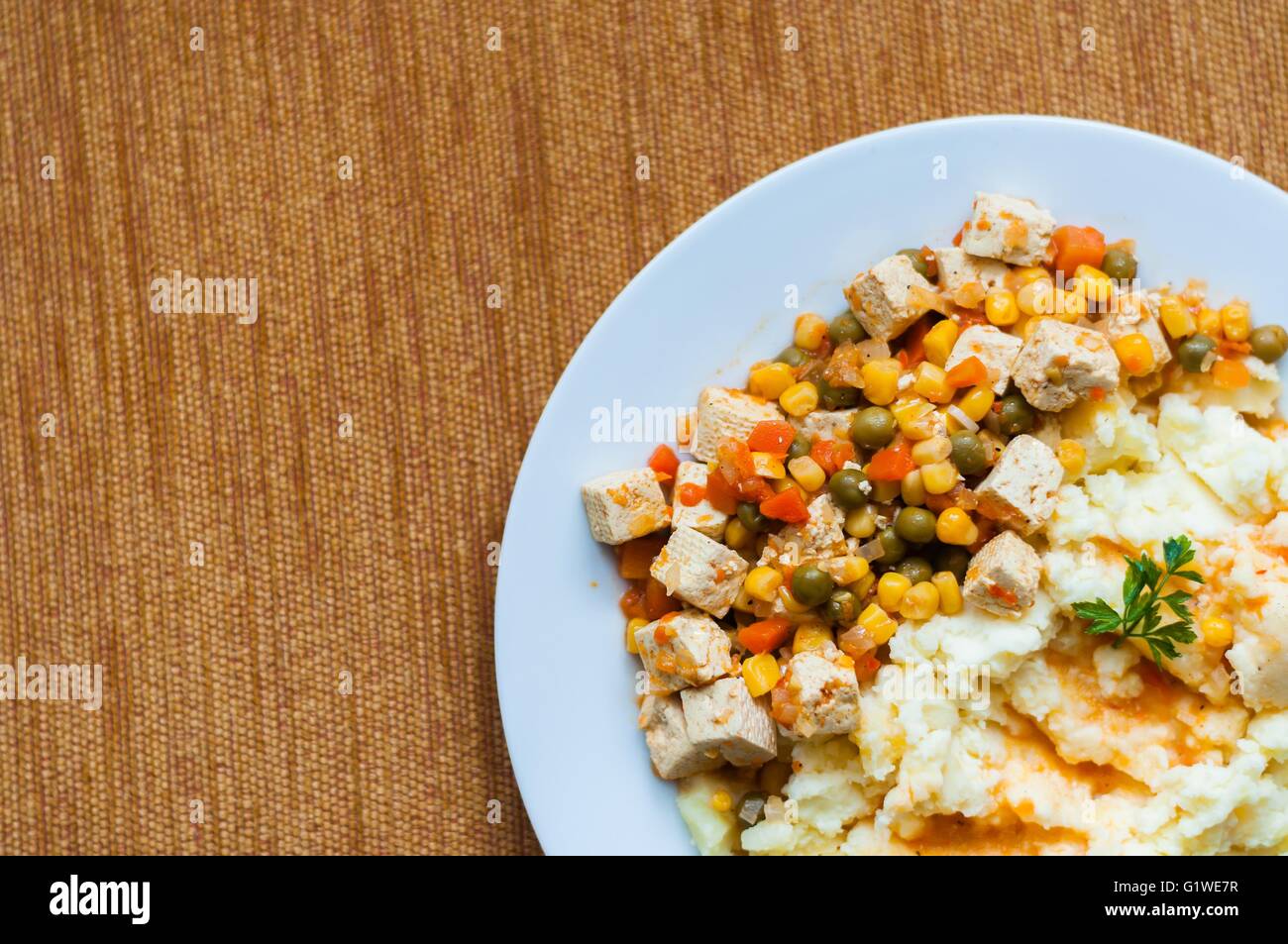 Healthy vegetarian cuisine with tofu with colorful roast vegetables including carrot, peas and maize served with mashed potatoes Stock Photo