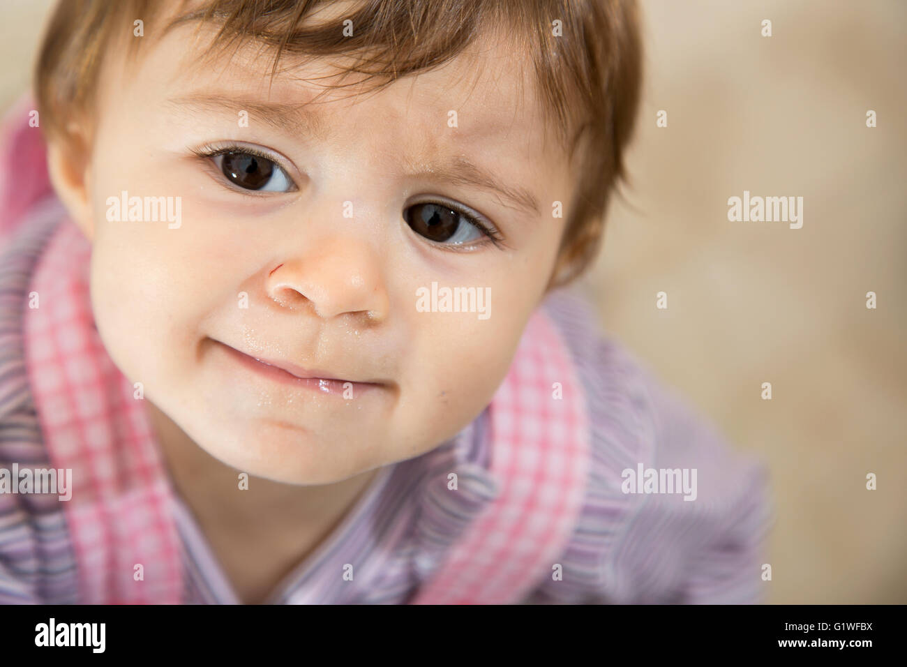 Close-up of cute one year old kid with brown eyes looking away sadly Stock Photo