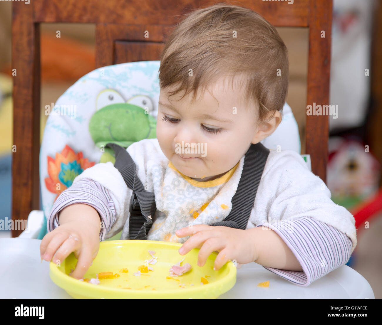 Portrait of lovely one year old baby eating with hands Stock Photo