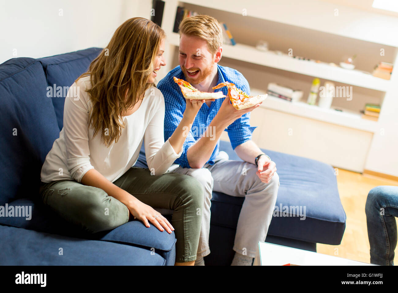 Couple eating pizza in the living room Stock Photo