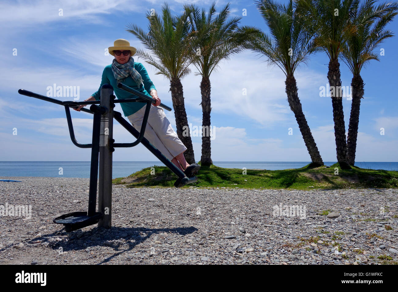 Woman using public keep fit exercise machines on Herradura beach in Spain Europe Stock Photo