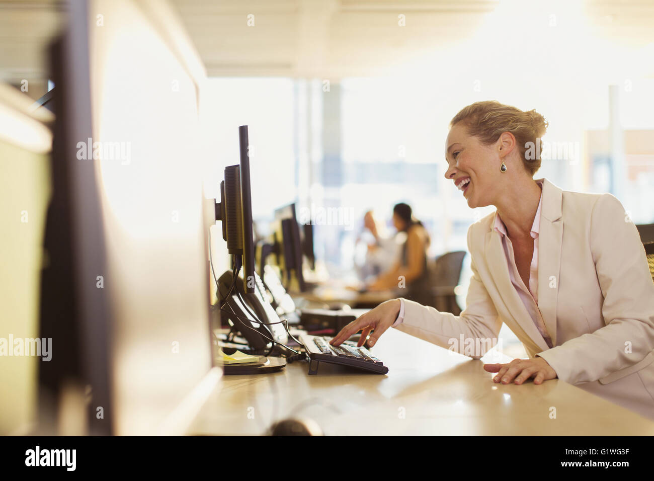 Laughing businesswoman working at computer in office Stock Photo