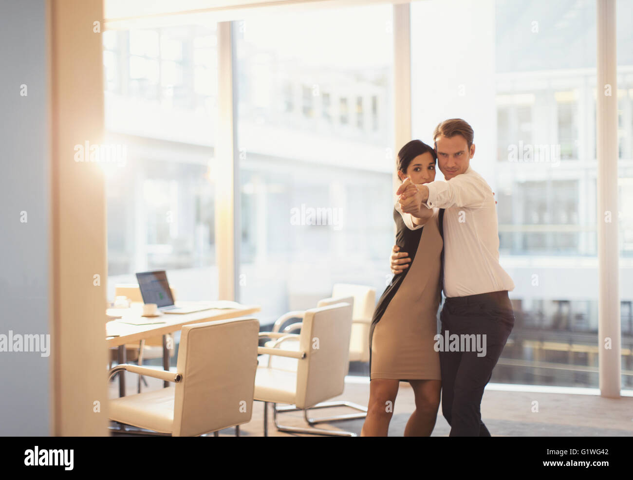 Businessman and businesswoman dancing in conference room Stock Photo