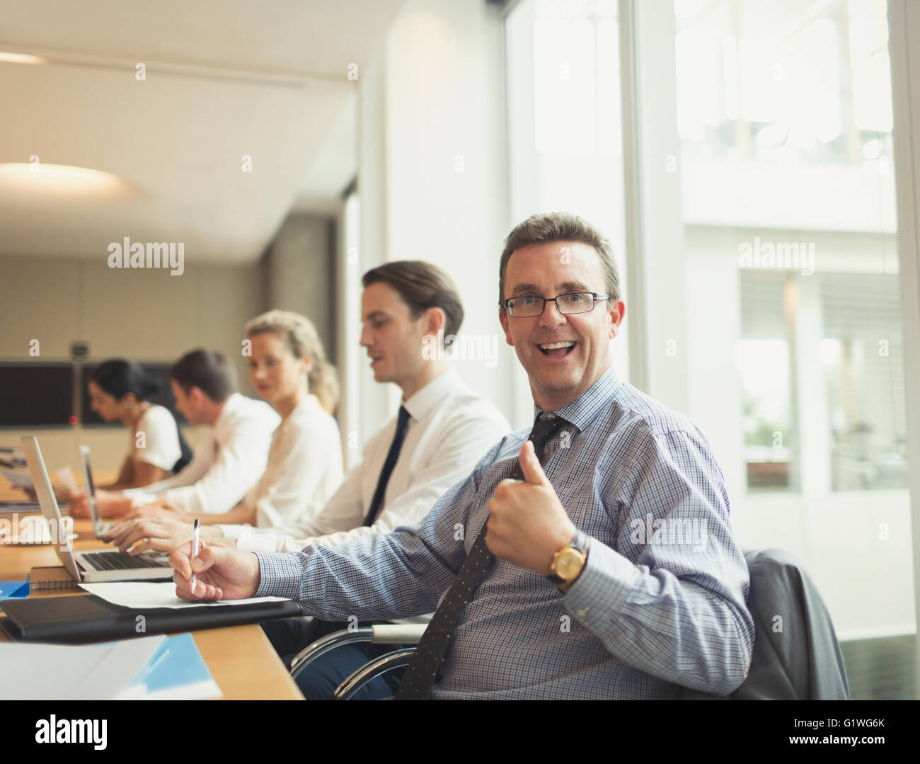Portrait of confident businessman gesturing thumbs-up in conference room meeting Stock Photo