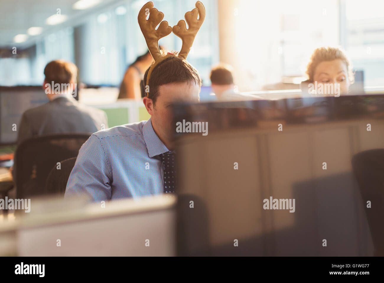 Businessman wearing antler headband in office Stock Photo
