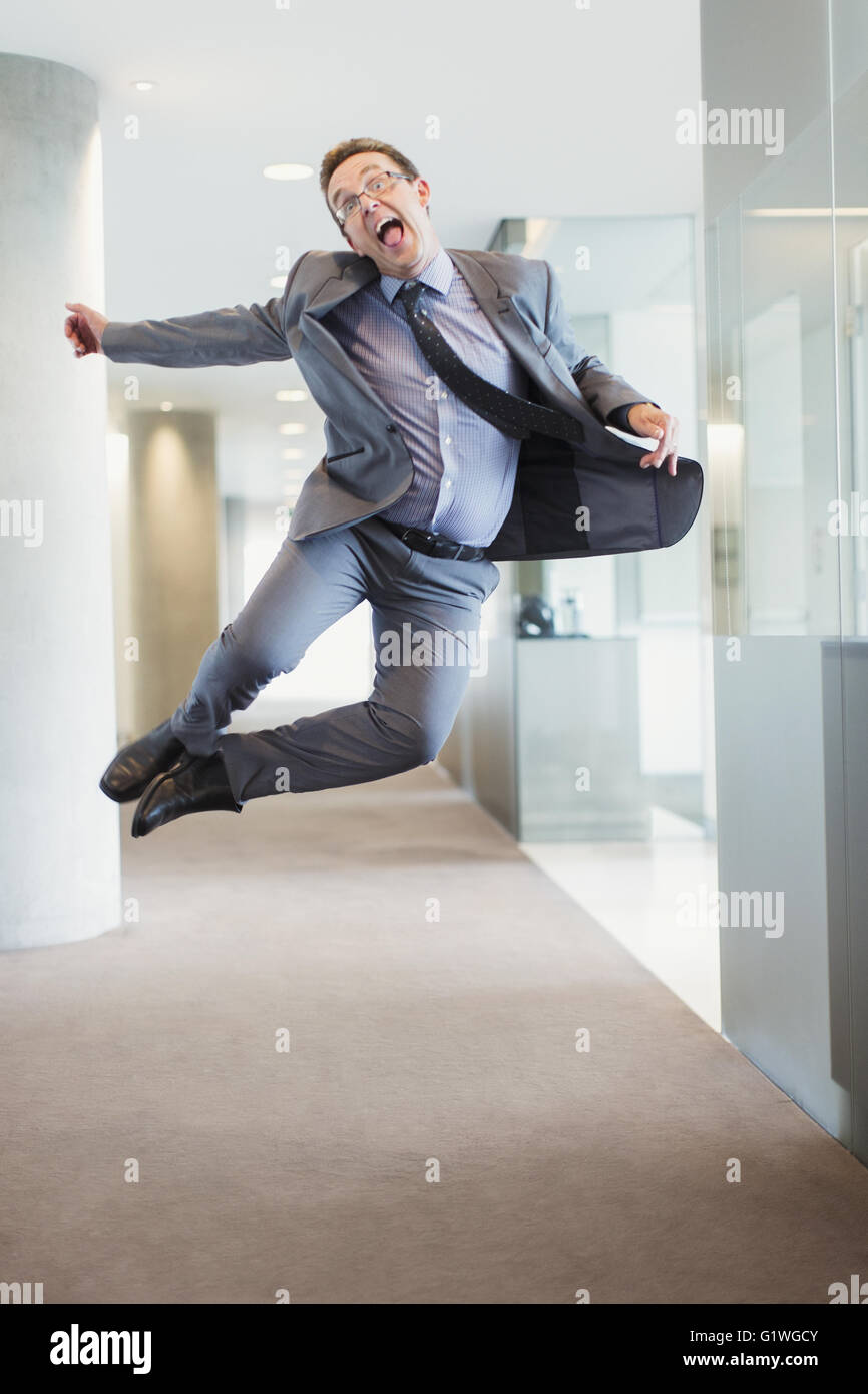 Exuberant businessman jumping for joy in office corridor Stock Photo