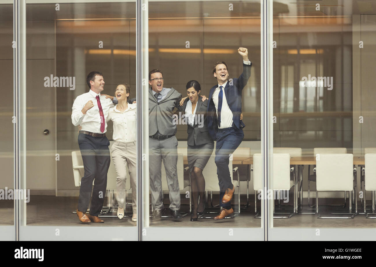 Business people celebrating and cheering at conference room window Stock Photo