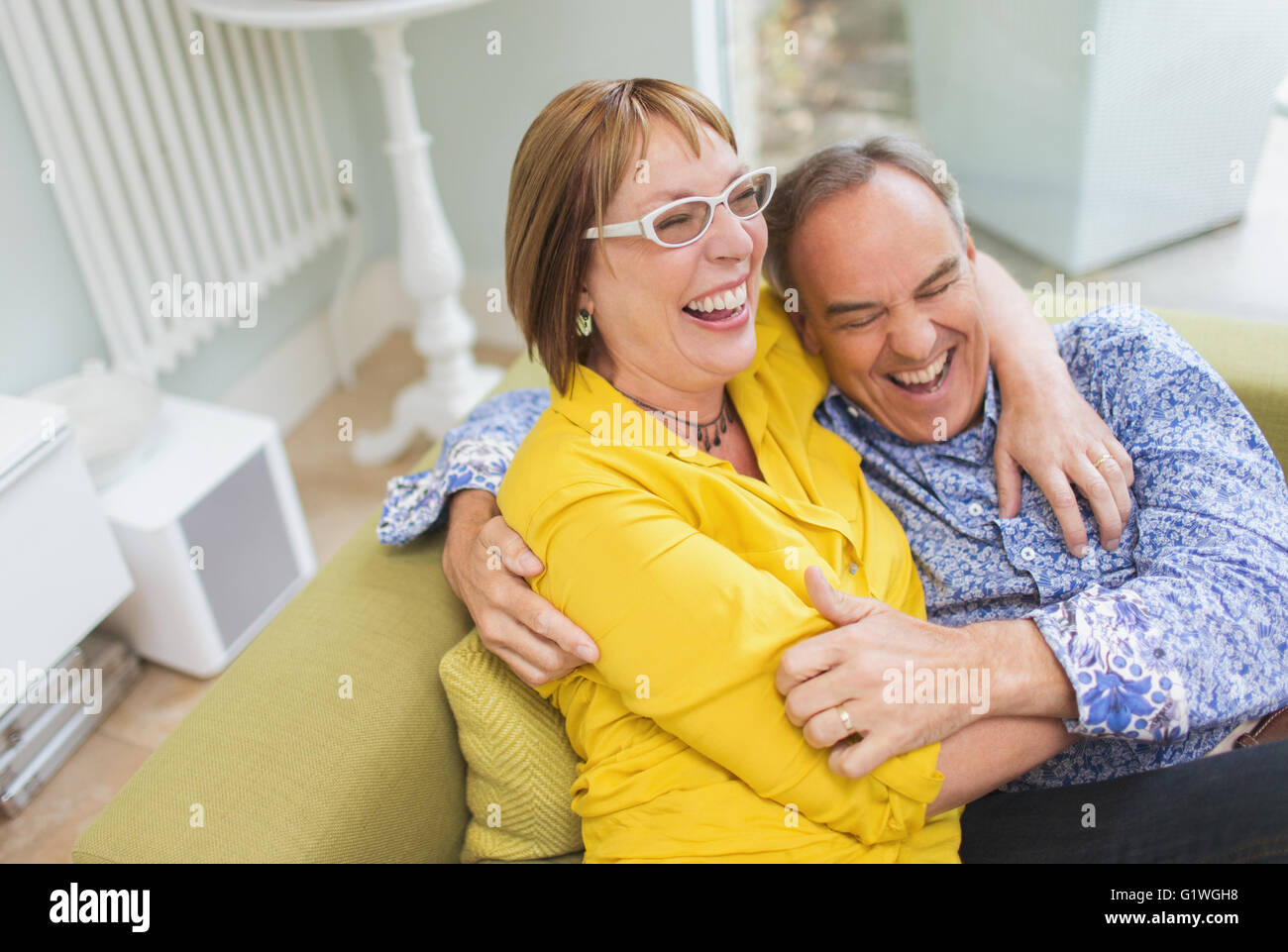 Mature couple laughing and hugging on sofa Stock Photo