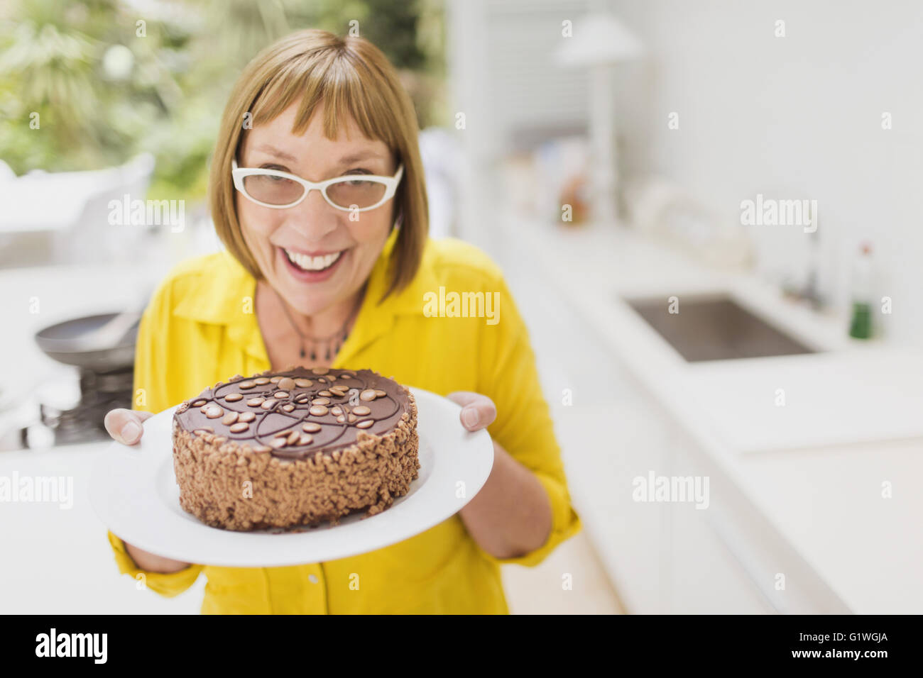 Portrait smiling mature woman holding chocolate cake Stock Photo