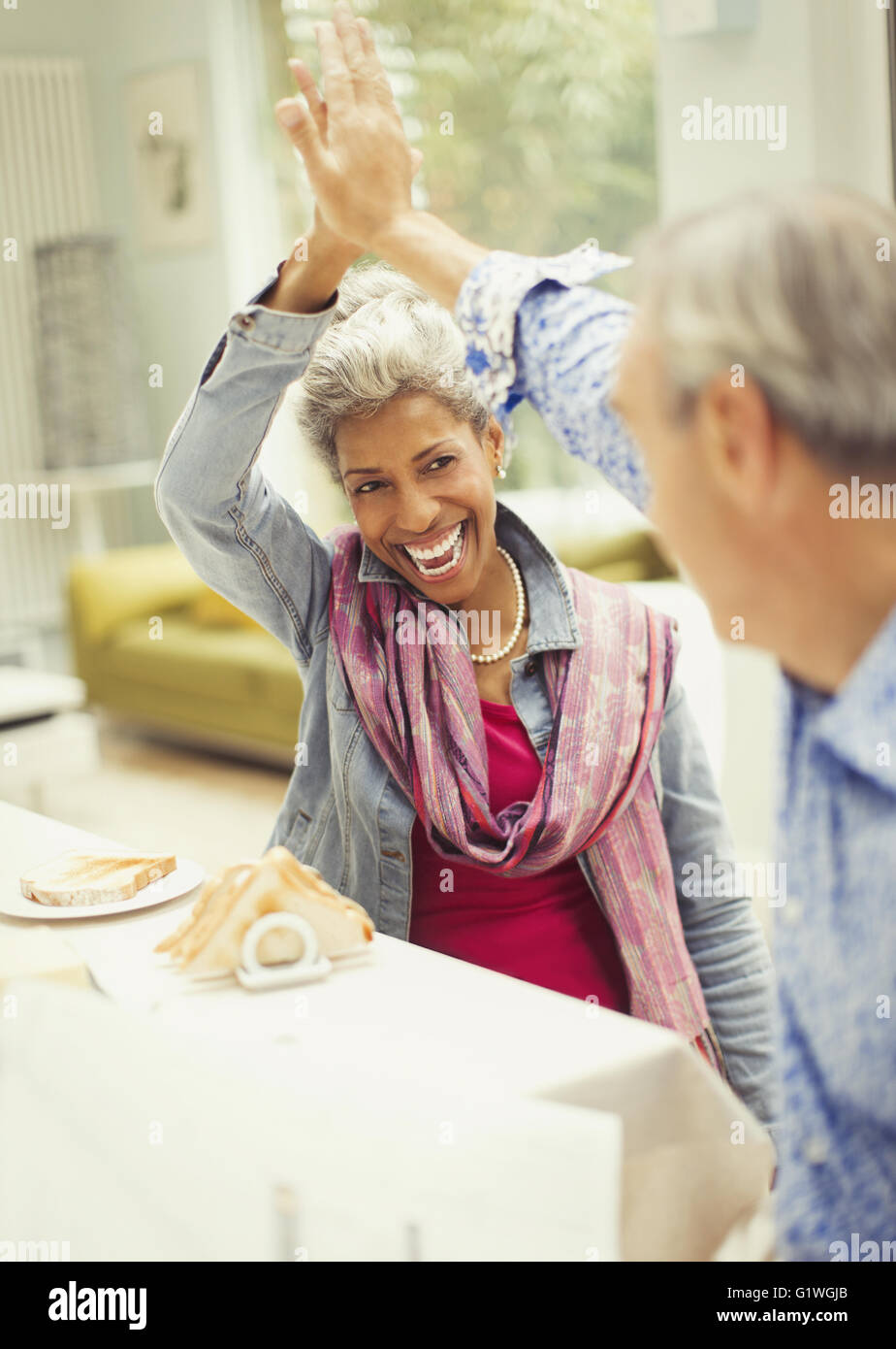 Enthusiastic mature couple high-fiving at breakfast Stock Photo