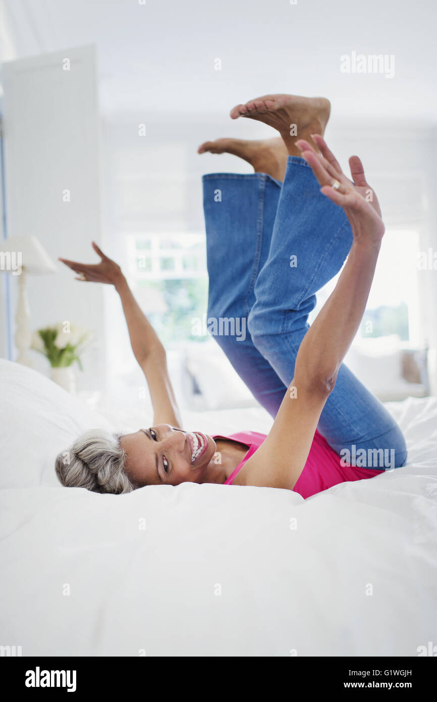 Portrait playful mature woman falling onto bed Stock Photo
