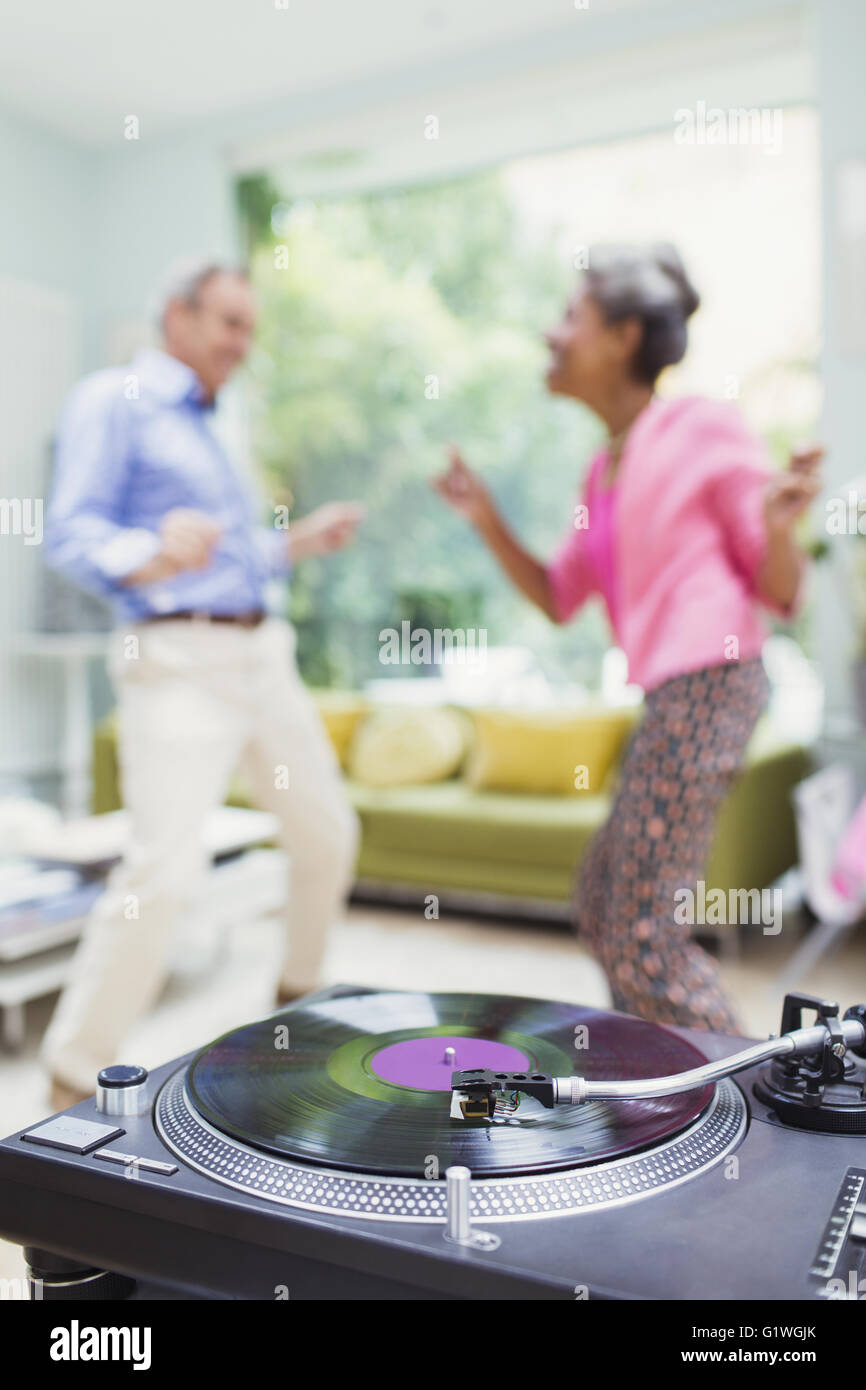 Playful nature couple dancing in living room behind record player Stock Photo