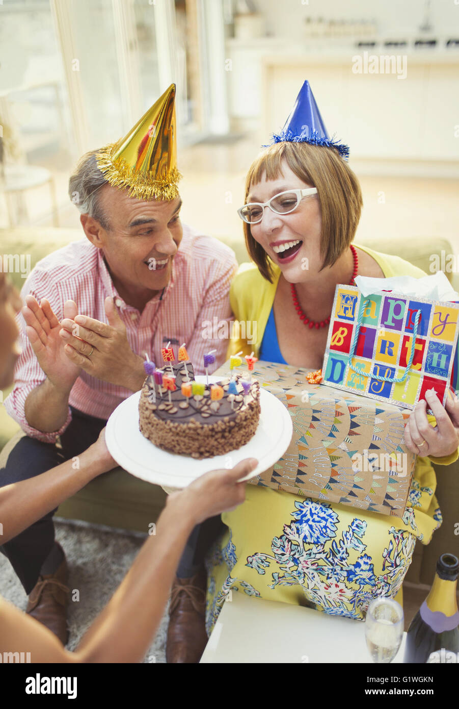 Smiling mature women receiving birthday cake and gifts Stock Photo