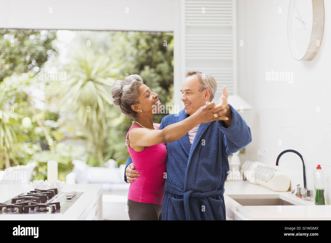 Playful mature couple dancing in kitchen Stock Photo