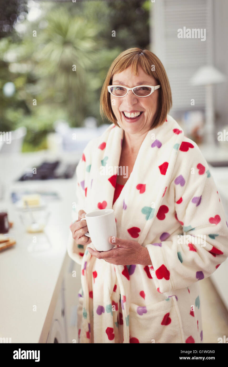 Portrait smiling mature woman drinking coffee in bathrobe Stock Photo