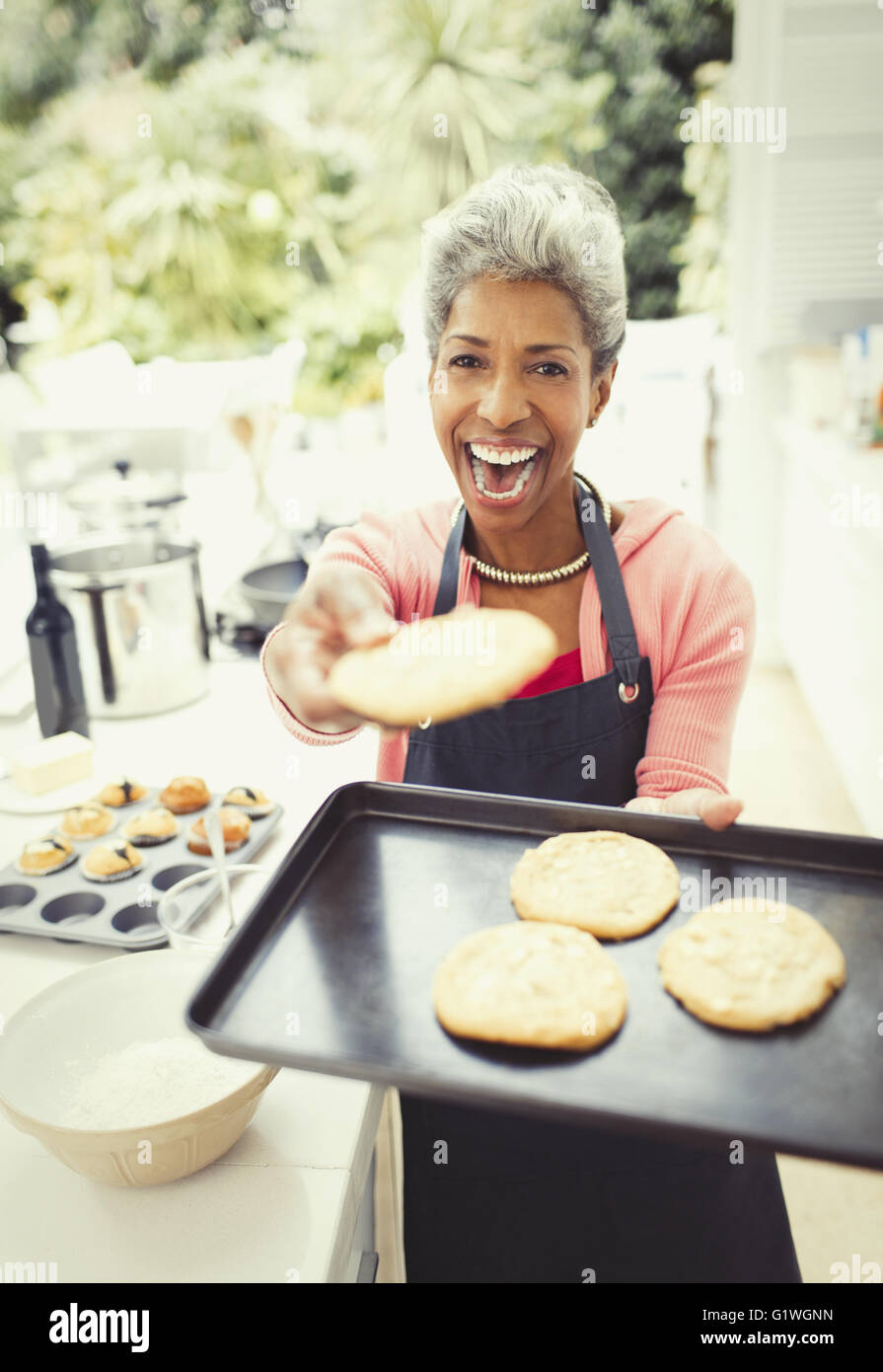 Portrait enthusiastic mature woman baking cookies in kitchen Stock Photo