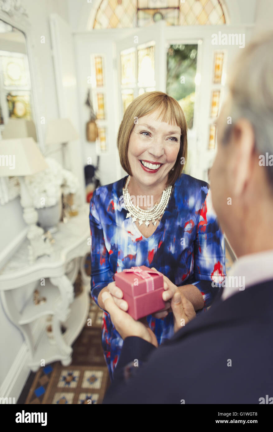 Smiling mature woman receiving gift from husband Stock Photo