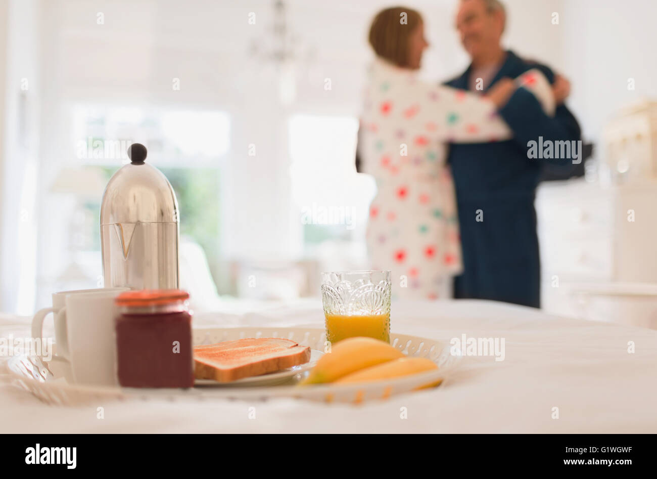 Mature couple in bathrobes dancing behind breakfast in bed Stock Photo