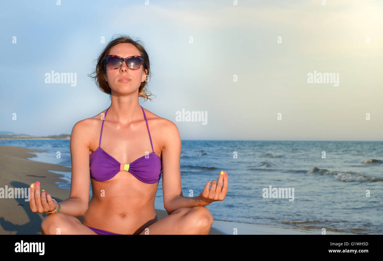 Young woman meditating alone at the empty beach Stock Photo