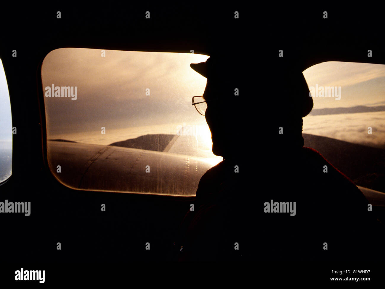 Adventure traveler in charter Bering Air airplane over Bering Sea at sunset; USSR; Russia: Siberia: Alaska Stock Photo