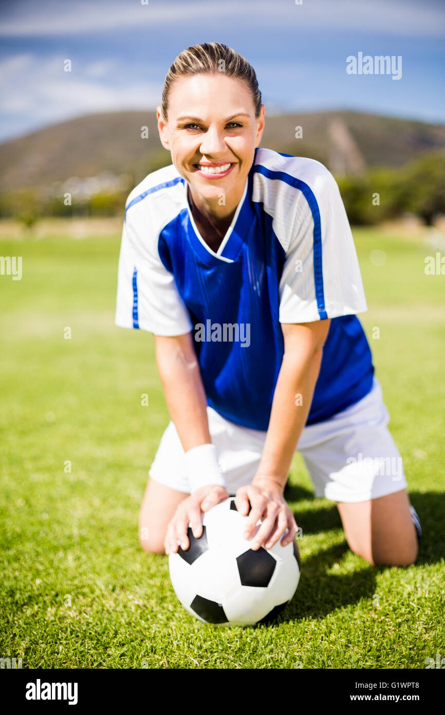 Female football player kneeling on field with ball Stock Photo Alamy
