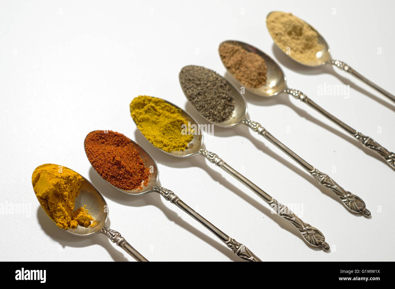 Various spices on vintage silver spoons Stock Photo