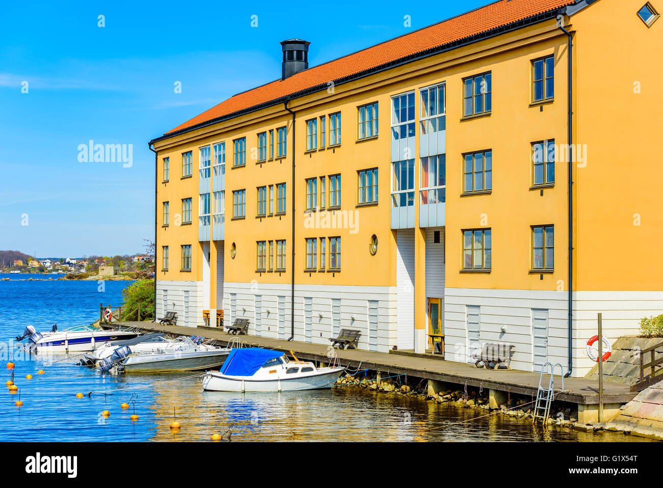 Karlskrona, Sweden - May 3, 2016: Coastal apartment building at Stumholmen in town. Building is yellow. Small recreational boats Stock Photo