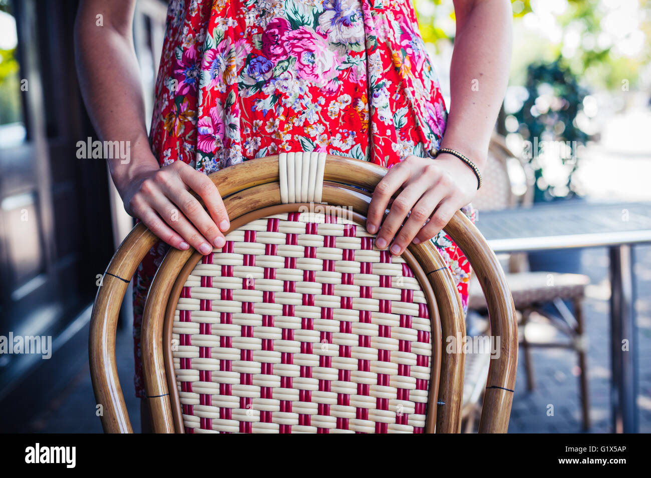 A Woman Is Standing Behind A Chair In The Street Outside A Cafe Stock a-woman-is-standing-behind-a-chair-in-the-street-outside-a-cafe-stock
