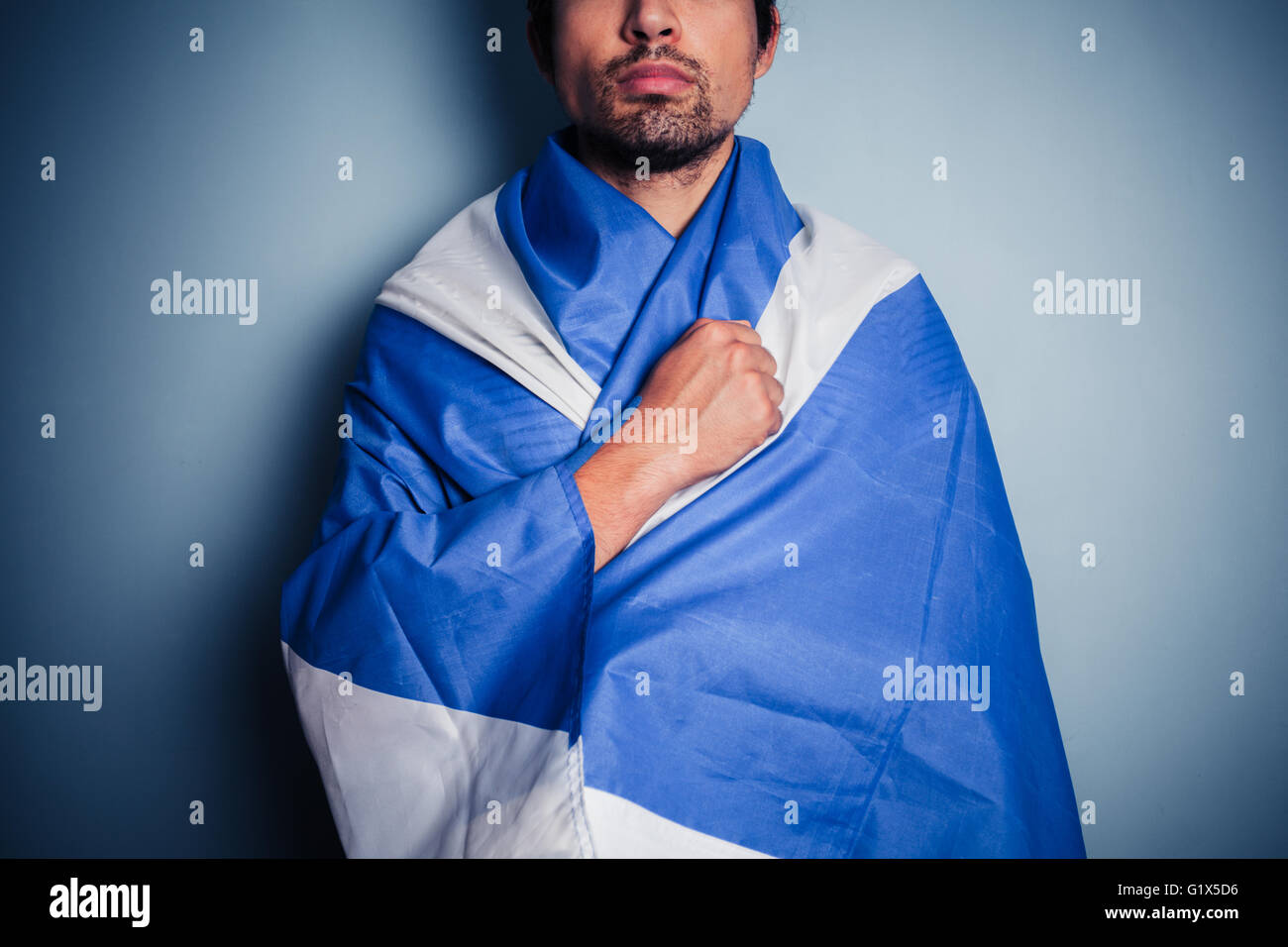 A brave and proud young Scotsman is wearing his nation's flag the saltire Stock Photo