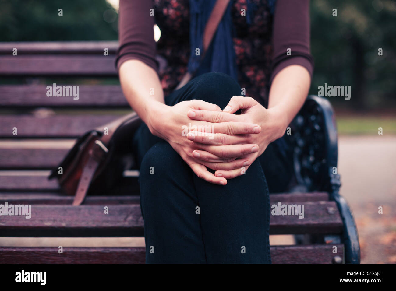 A young woman is sitting on a park bench in the autumn Stock Photo - Alamy