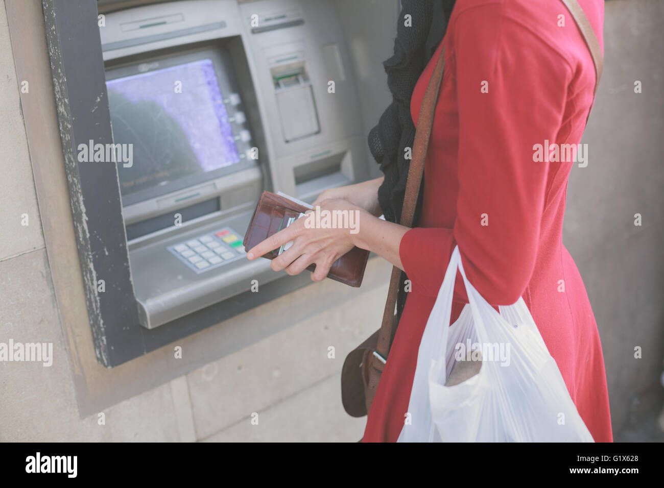 A young woman is withdrawing money from an ATM Stock Photo