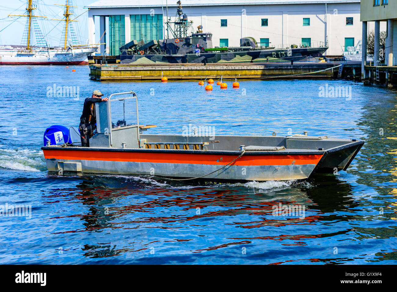 Karlskrona, Sweden - May 3, 2016: Male person driving an open motorboat through the canal with the maritime museum in the backgr Stock Photo