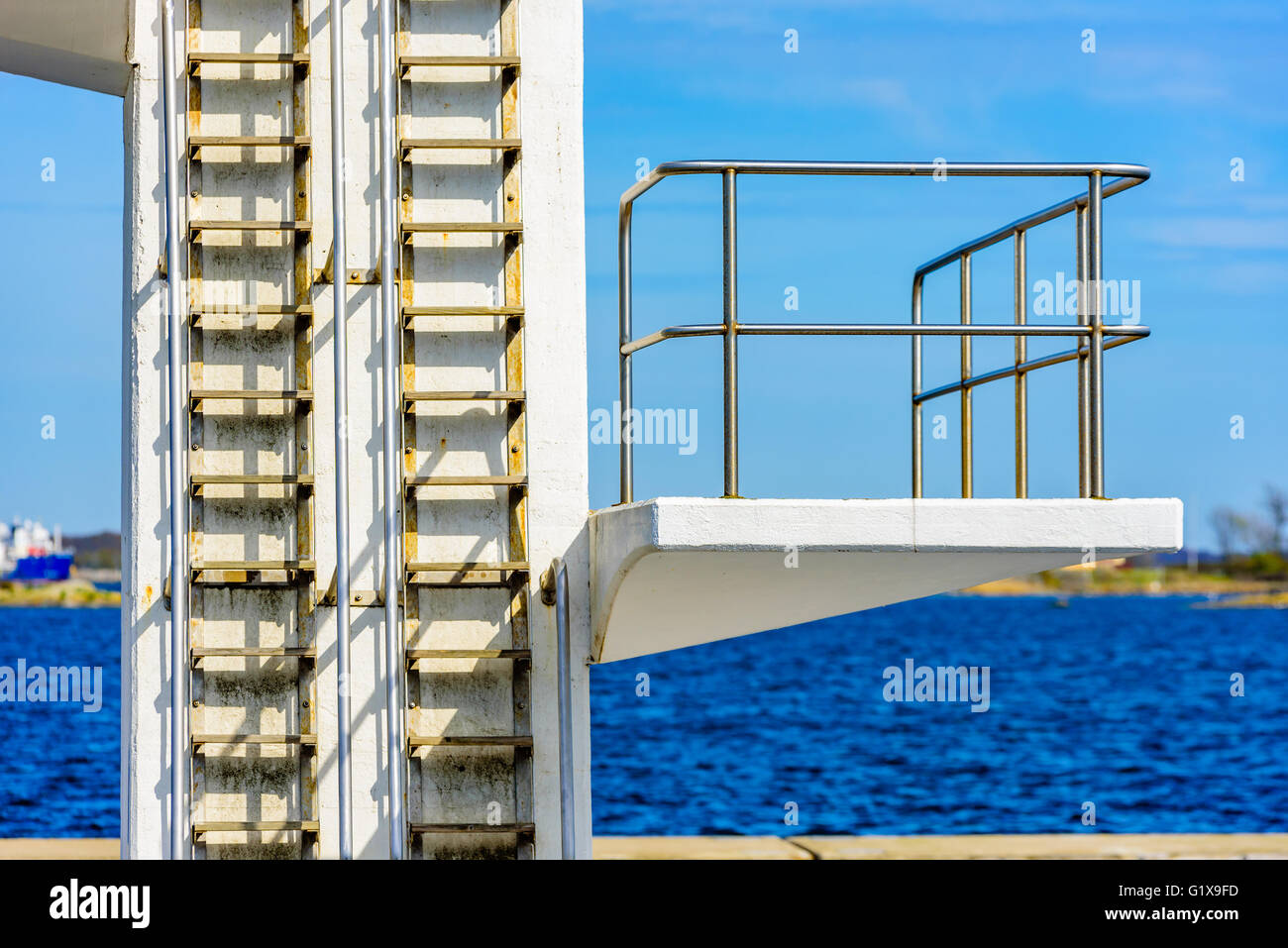 Detail of a white public diving tower or diving platform against a blue sky. Stock Photo