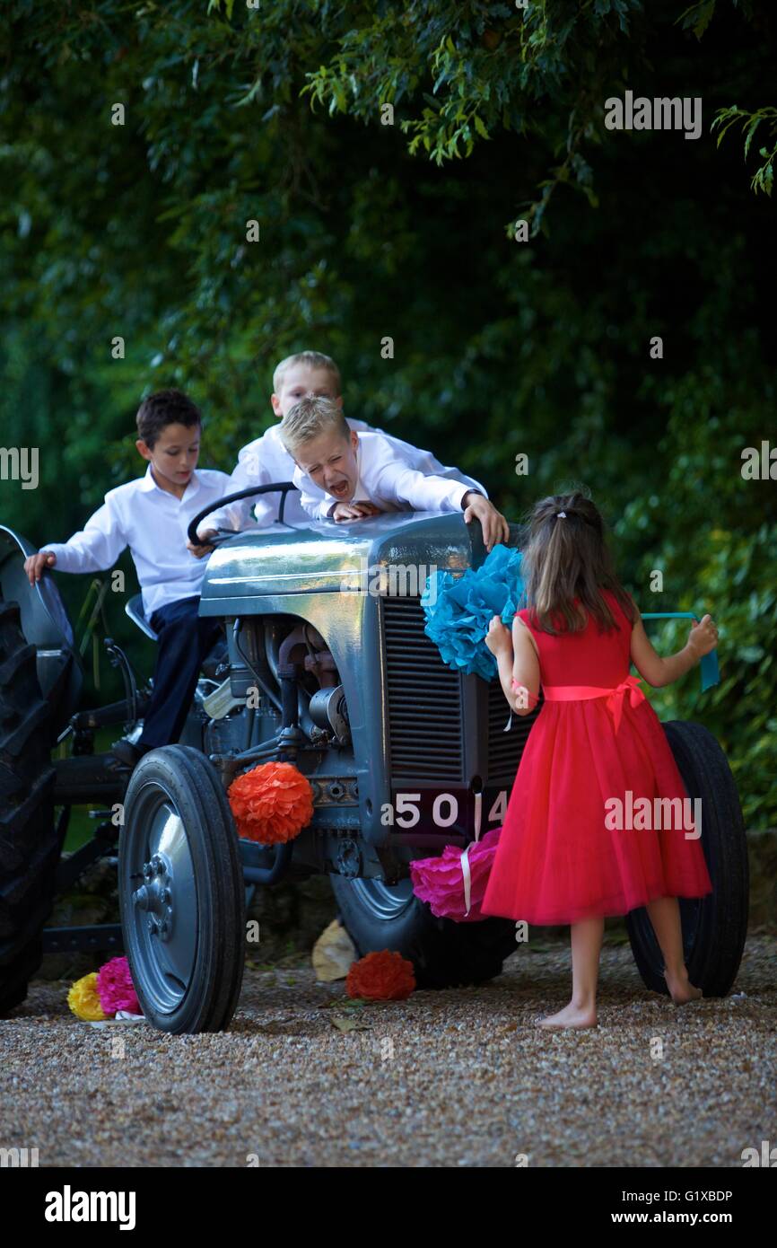 Children Playing on old fashioned tractor during a wedding party Stock Photo