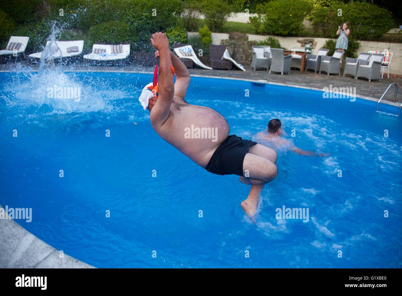 Overweight adult male jumping in swimming pool Stock Photo