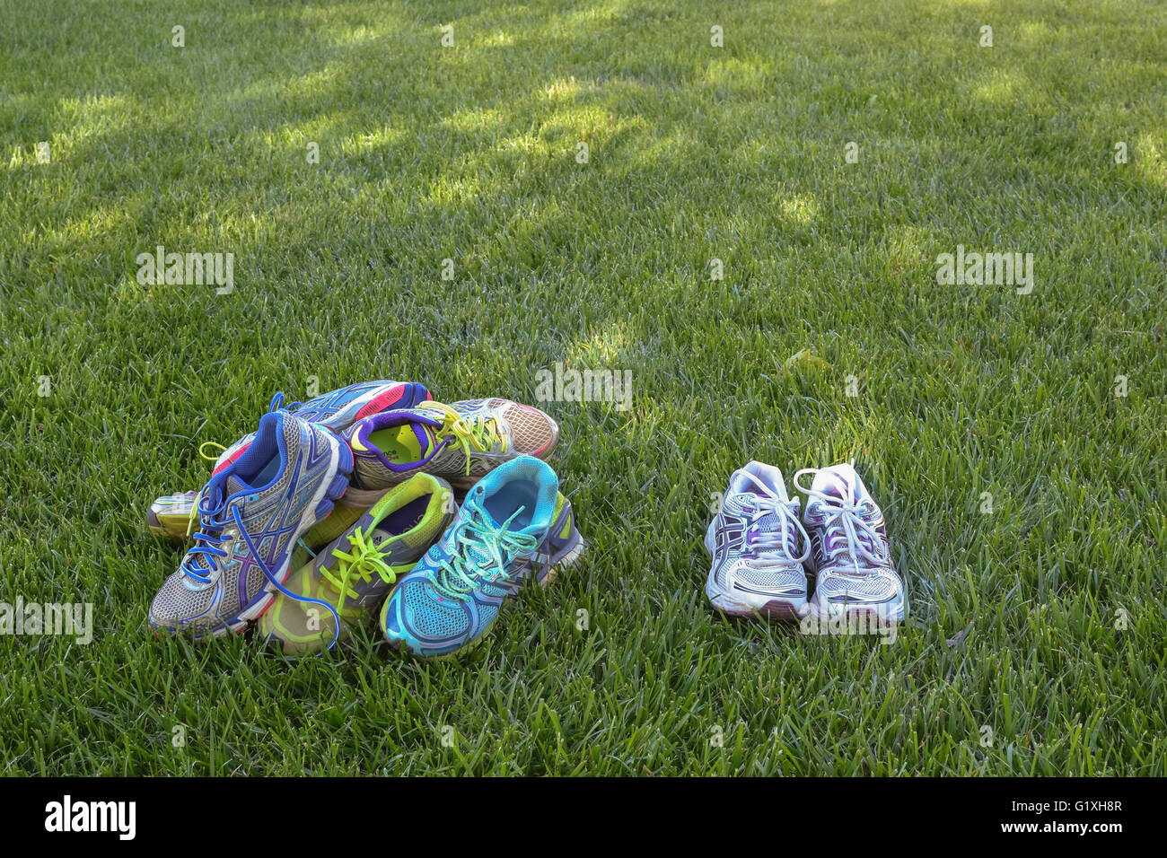 A pile of old running shoes beside a new pair. Stock Photo