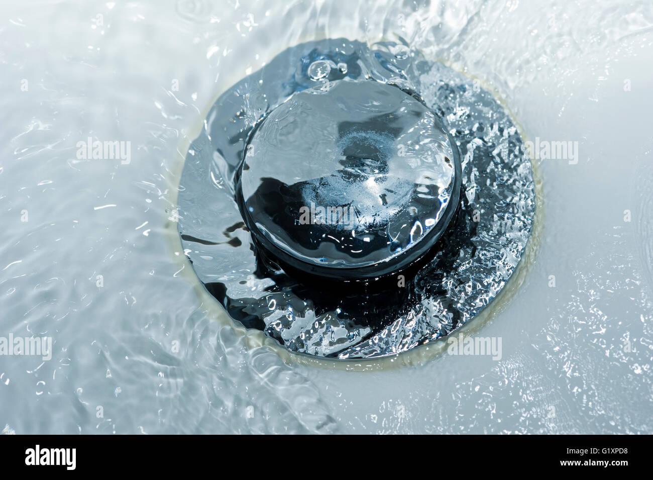 Water pouring down a sink plughole Stock Photo