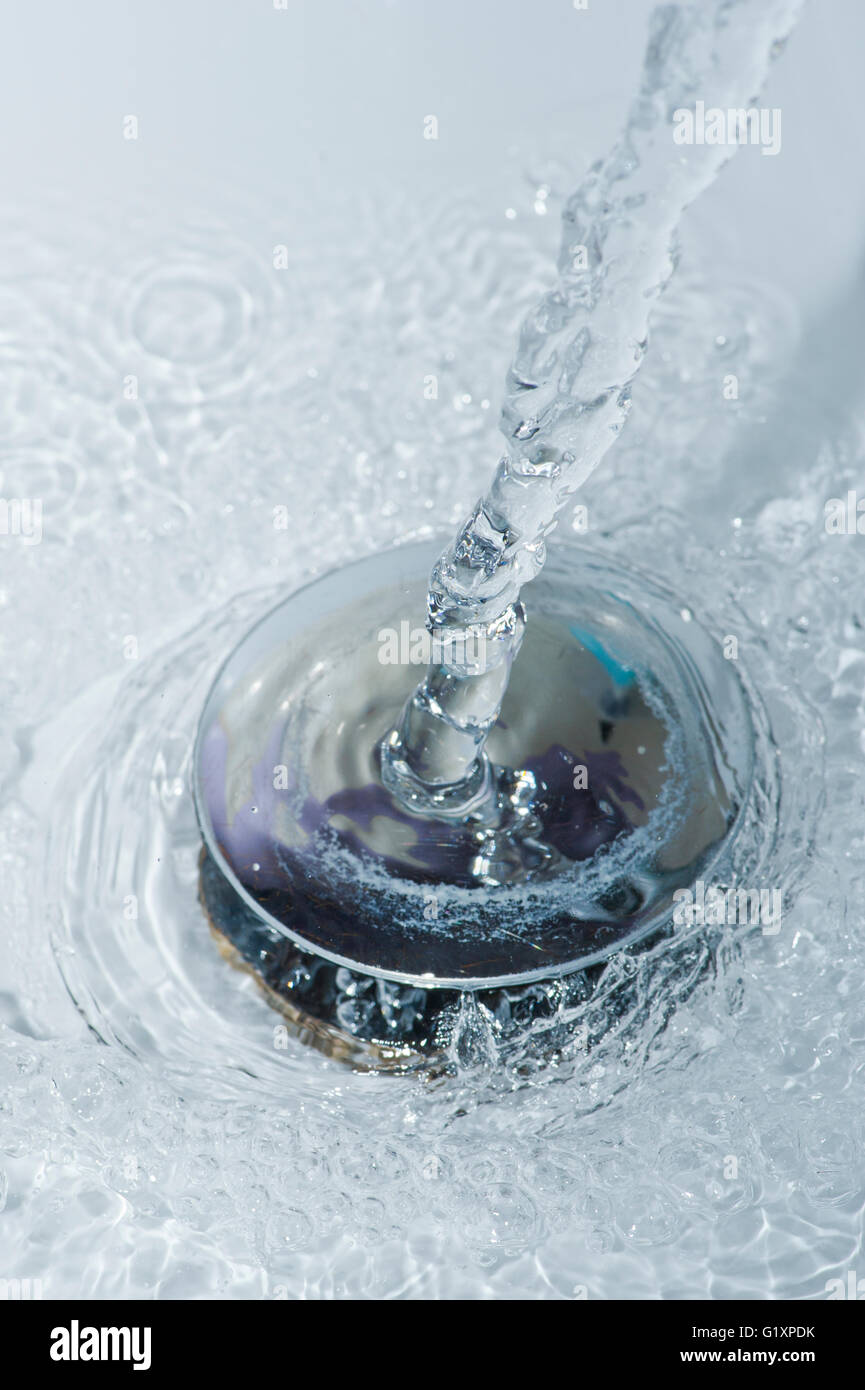 Water pouring down a sink plughole Stock Photo