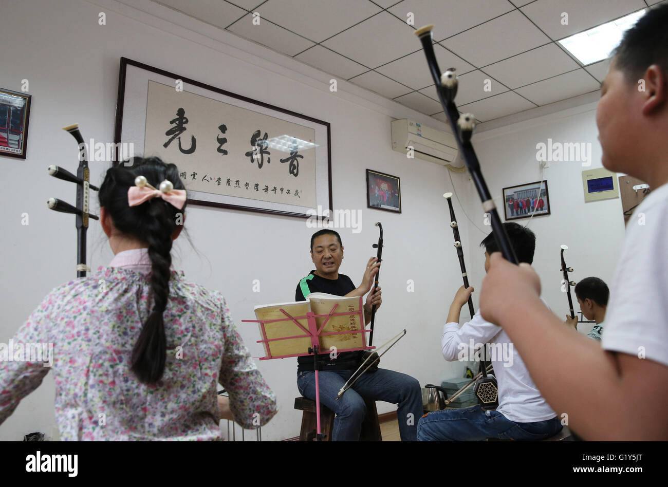 Zhengzhou, China. 20th May, 2016. Li Chaoyi, founder of a non-profit instrumental training organization for disabled children, teaches blind children Erhu, a two-stringed bowed musical instrument, in Zhengzhou, capital of China, May 20, 2016. The organization founded by Li Chaoyi in 2014 has over ten volunteers by now, who have been teaching more than 50 blind children on music instruments like Erhu. © Zhao Peng/Xinhua/Alamy Live News Stock Photo