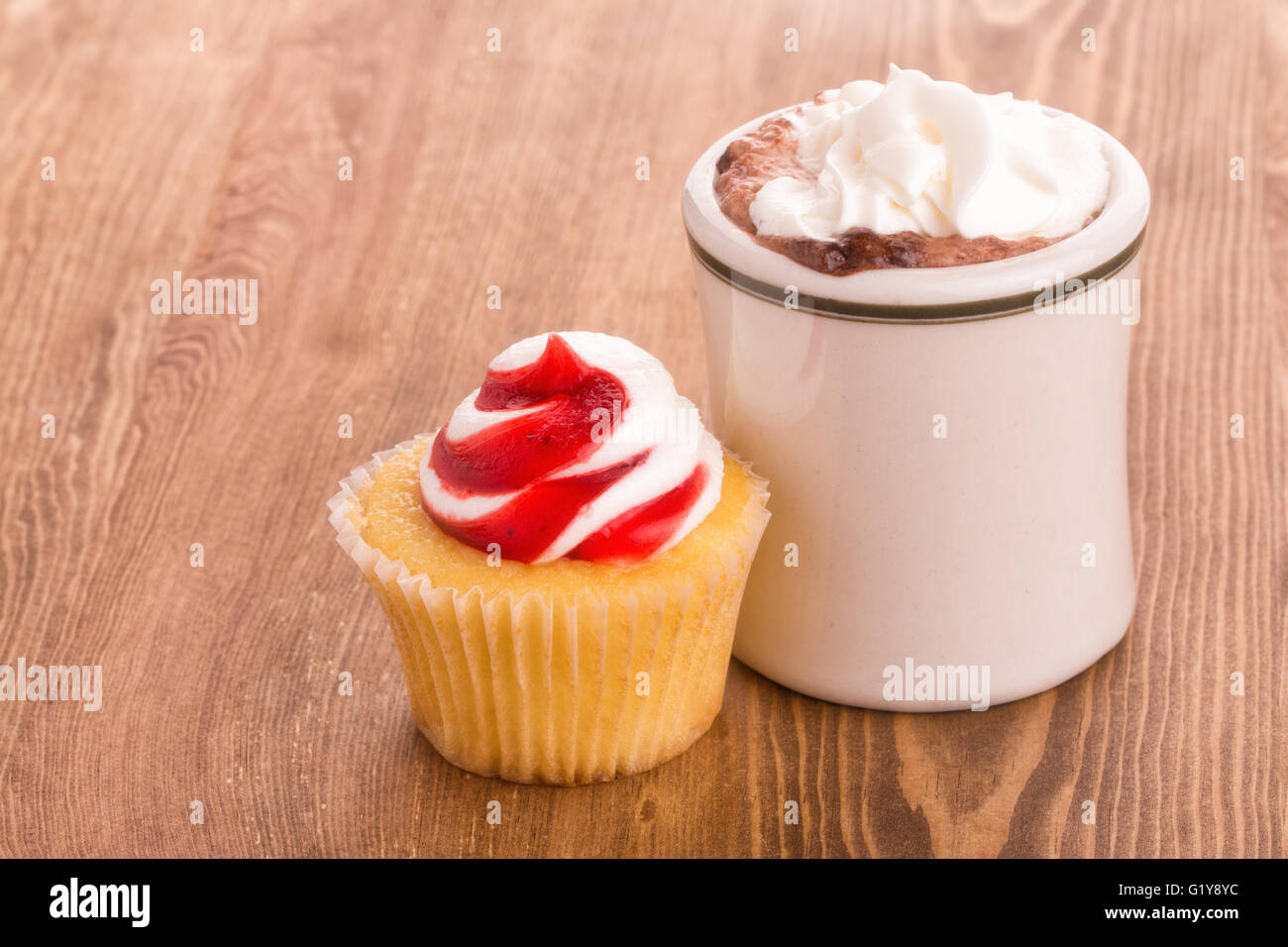Strawberry cupcake with a cup of hot chocolate on wooden tabletop - with a slight softening filter for a nostalgic effect Stock Photo