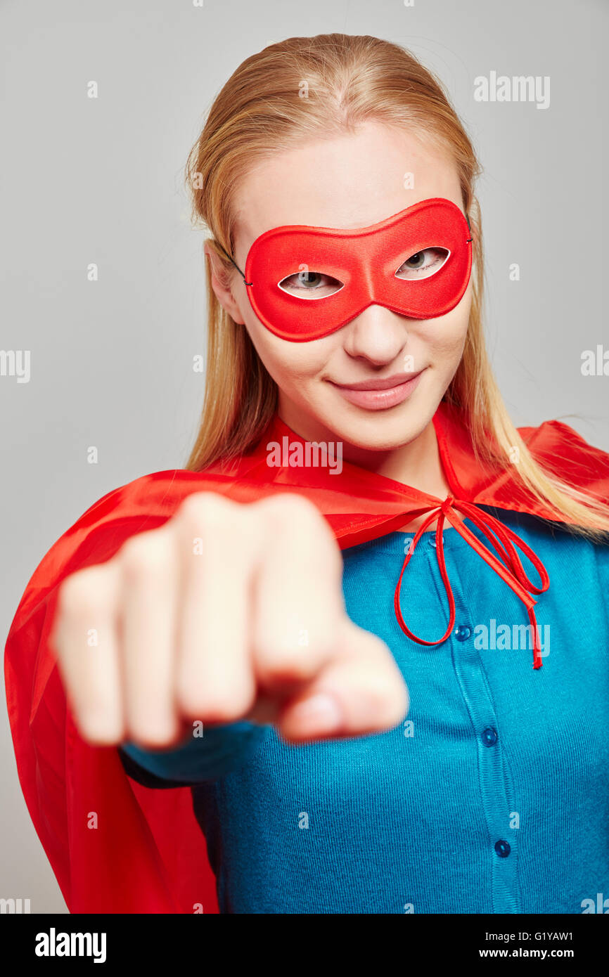 Strong woman dresses as a superhero for carnival Starke Frau als Superheld zu Karneval clenching her fist Stock Photo