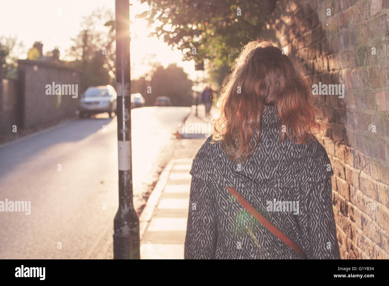 A young woman is walking into the sunset on an autumn day in the city ...