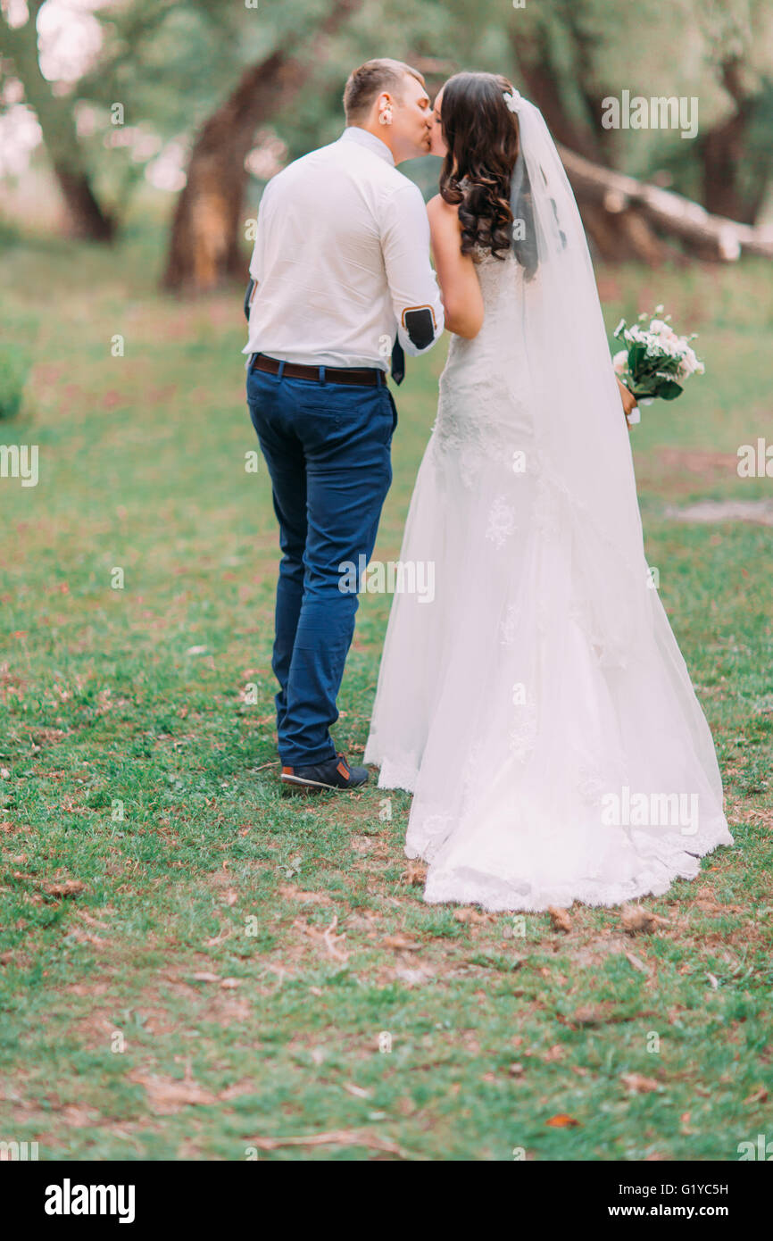 Beautiful married couple walking back holding hands and kissing on the ...