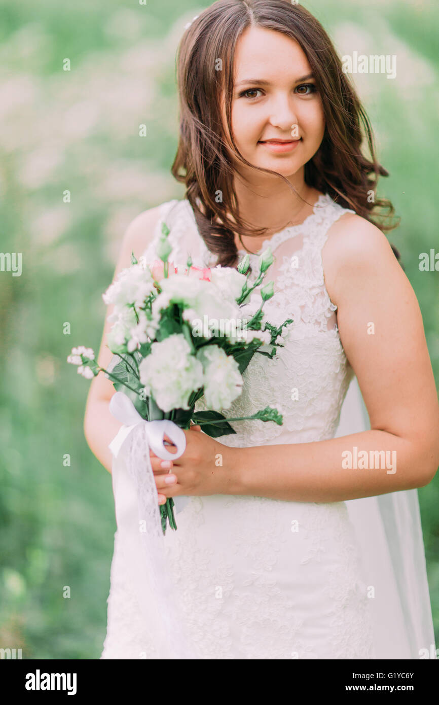 Portrait of beautiful smiling bride holding bouquet while standing in ...
