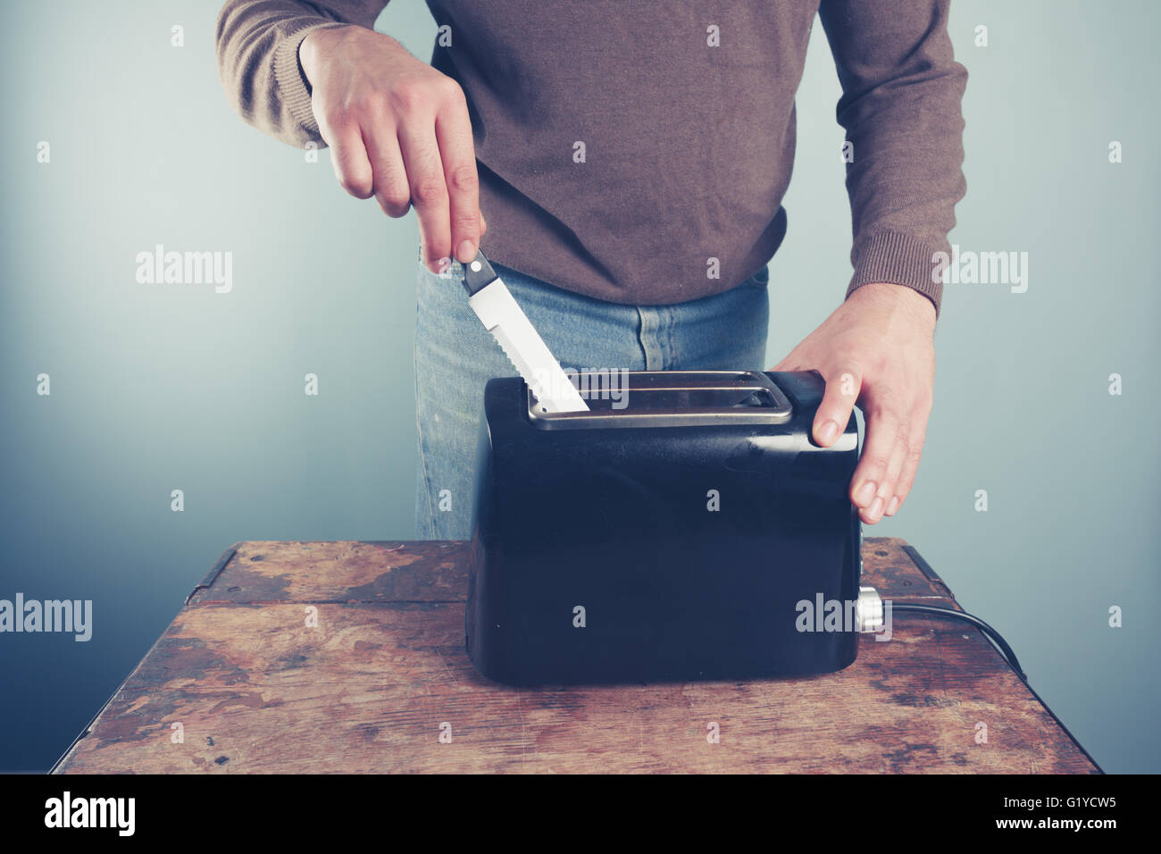 A young man is sticking a knife into an electric toaster Stock Photo Alamy