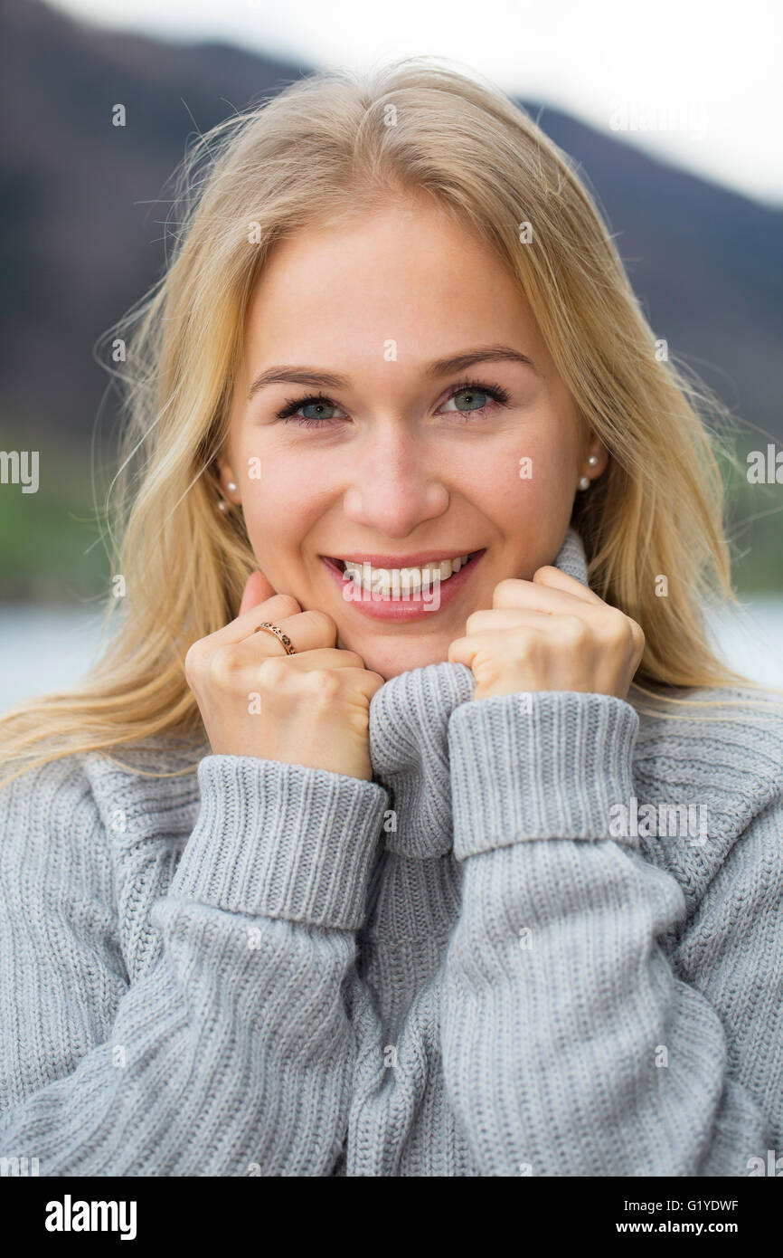 Portrait of a laughing young woman with long blond hair umd warm sweater Stock Photo